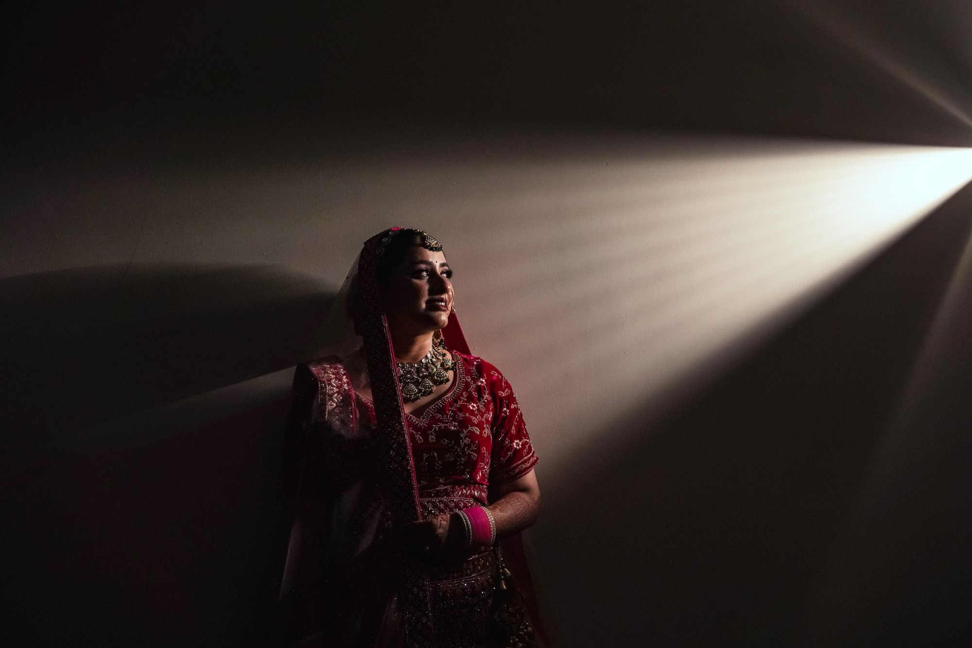 A breathtaking moment as the bride admires the sunlight piercing through a tiny gap in the dark room.