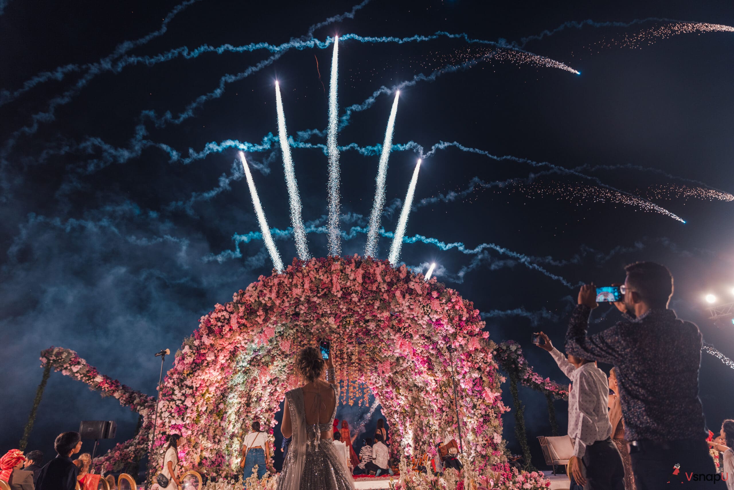 A dreamy wedding night as the bride and groom gaze at fiery fireworks above.