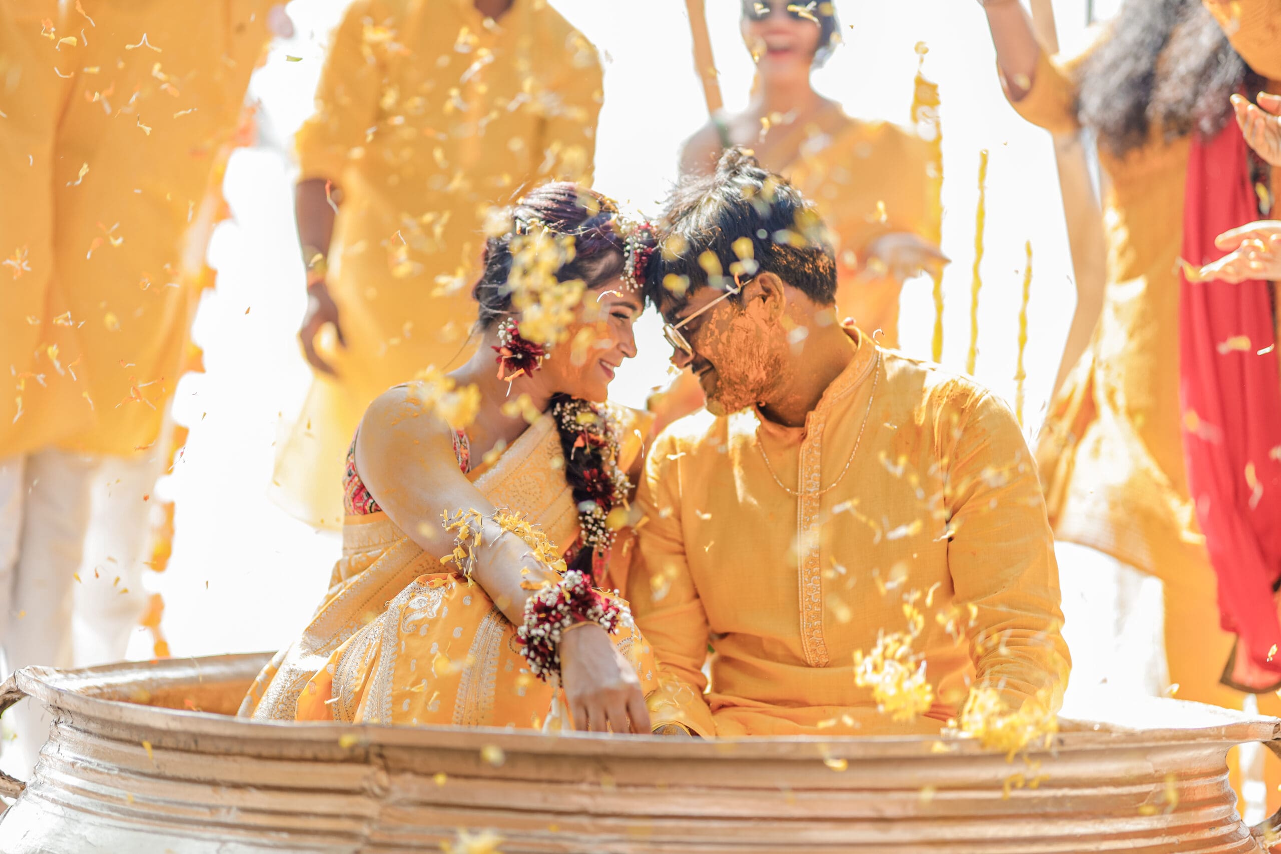 The groom and bride’s heads meet in a sweet gesture during their haldi ceremony, symbolizing their bond.