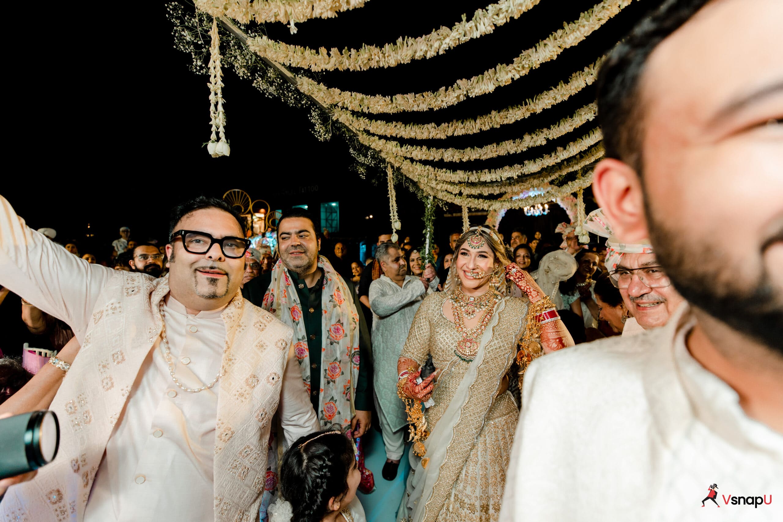 The bride shines brightly as she walks into the ceremony with her brothers, bathed in beautiful lighting.