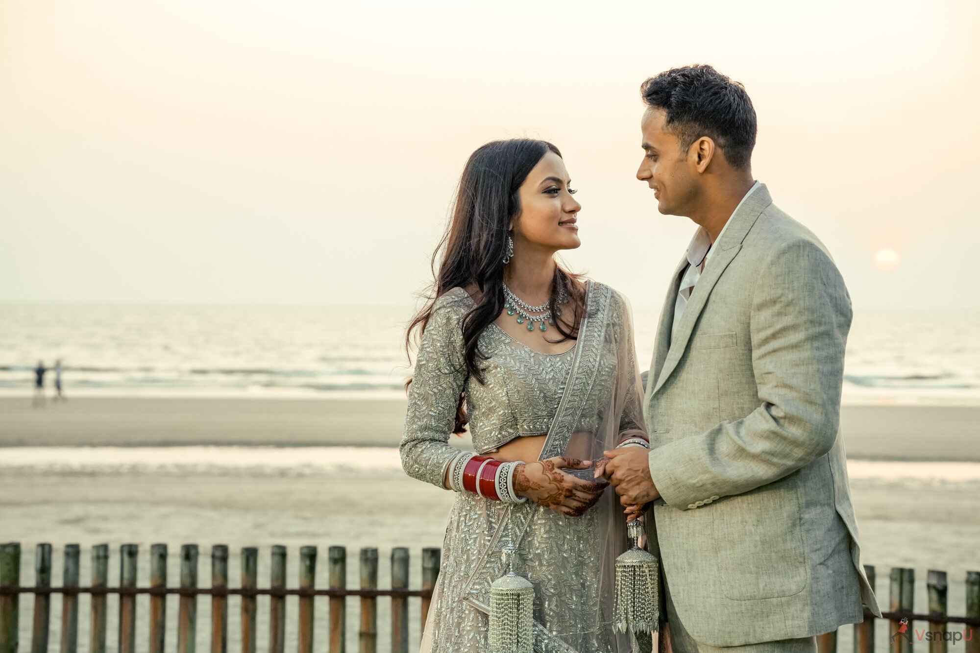 In the warm sunlight, the groom and bride gaze lovingly at each other, captured by VsnapU during their destination wedding in Jim Corbett.